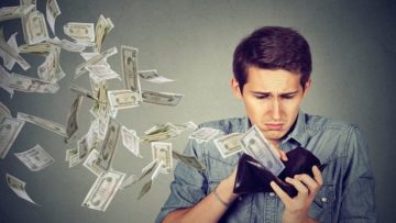 Man looking at wallet with money dollars flying away